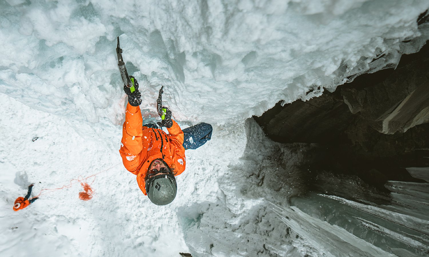 The North Face team athlete Jackson Marvell ascends an icy climb in bright orange Summit Series gear.