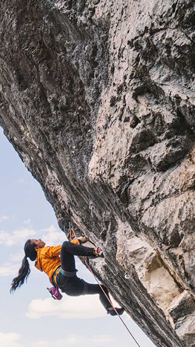 A female climber ascends a near vertical wall.