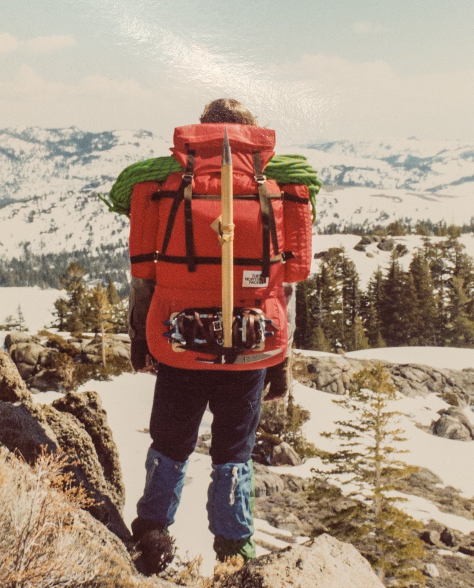 A backpacker treks through the snow-covered mountains wearing a fully packed.