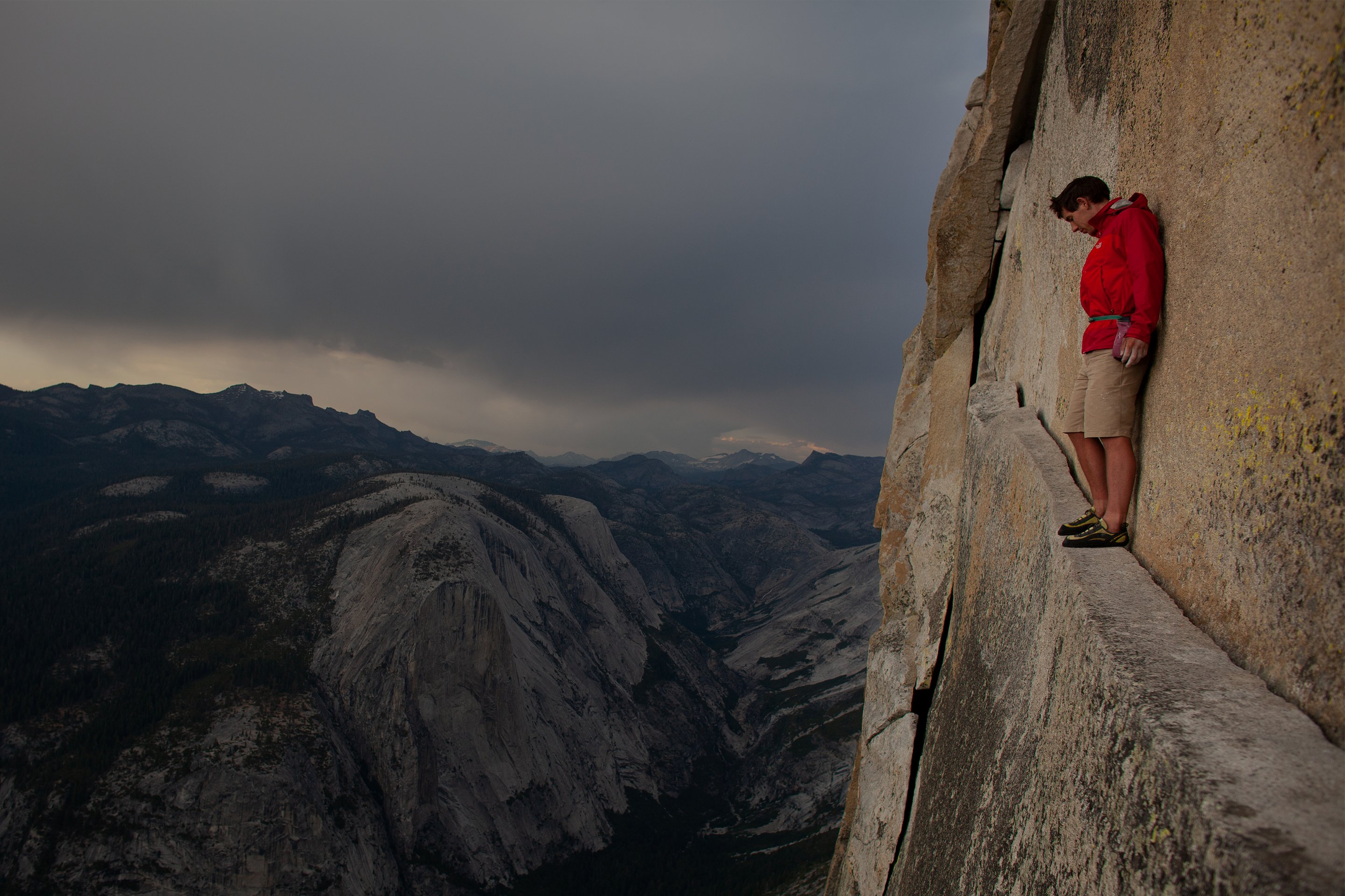 Climber, Alex Honnold, looks down on the Yosemite Valley from an exposed ledge.
