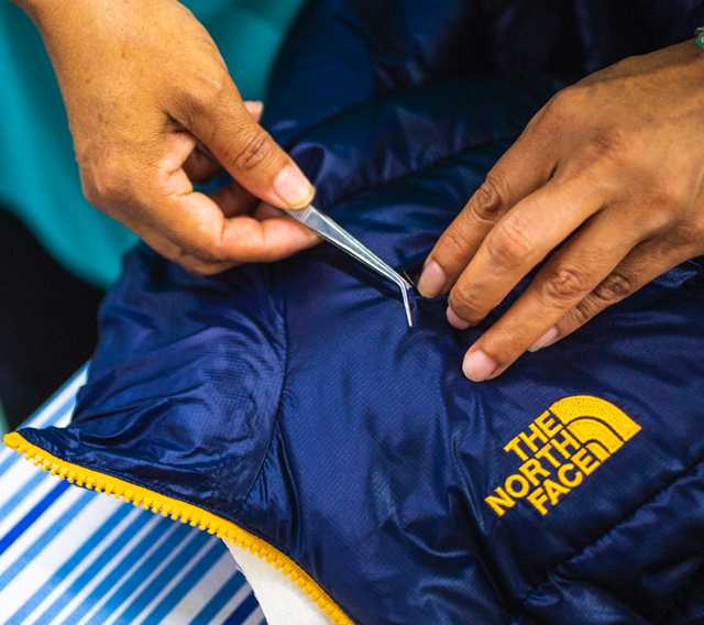 A jacket is carefully repaired so it can be reused on future adventures.
