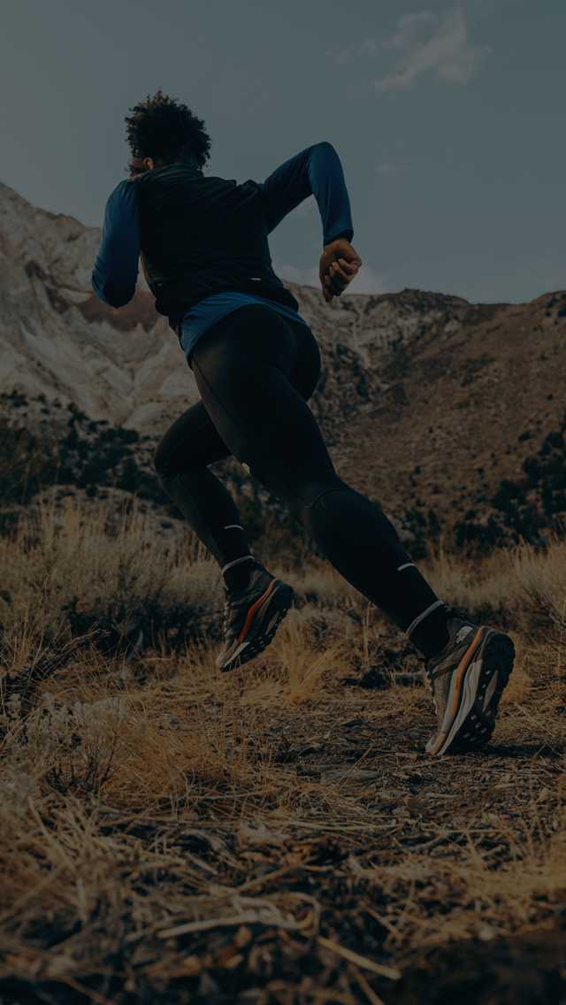 A trail runner sprints through a rugged mountain setting.
