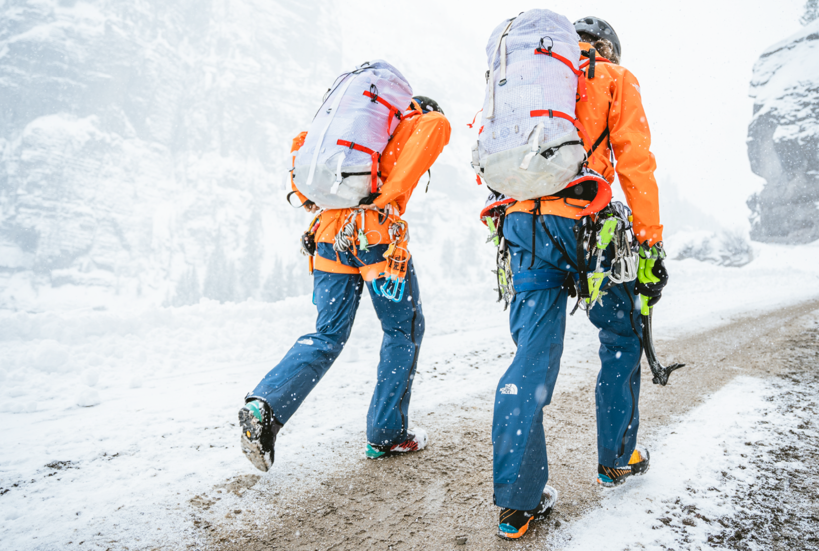 Two geared-up mountaineers walk confidently into icy winter conditions in the high-alpine.