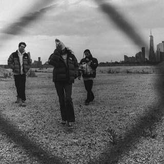 Three people wearing the new ’92 Nuptse from The North Face stand in a field. A city skyline is behind them