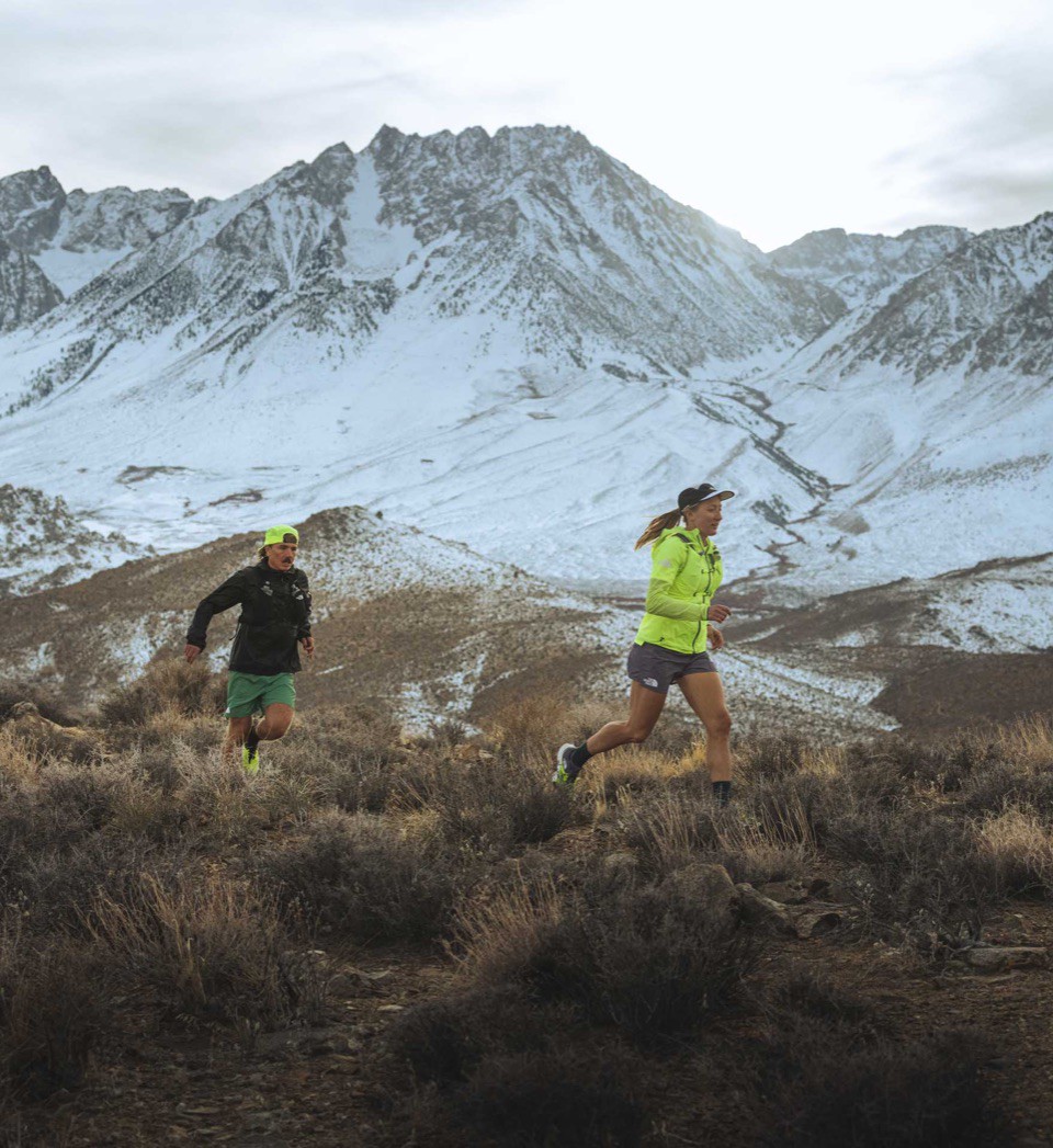 Two runners power to the summit of a high alpine trail.